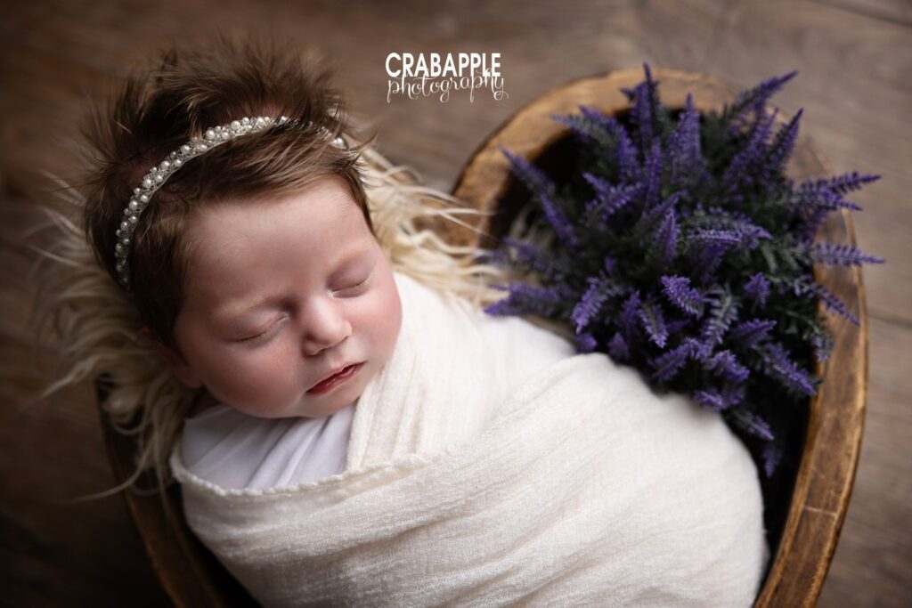 Newborn baby in heart shaped wooden bowl for portraits with floral touches and pearl headband