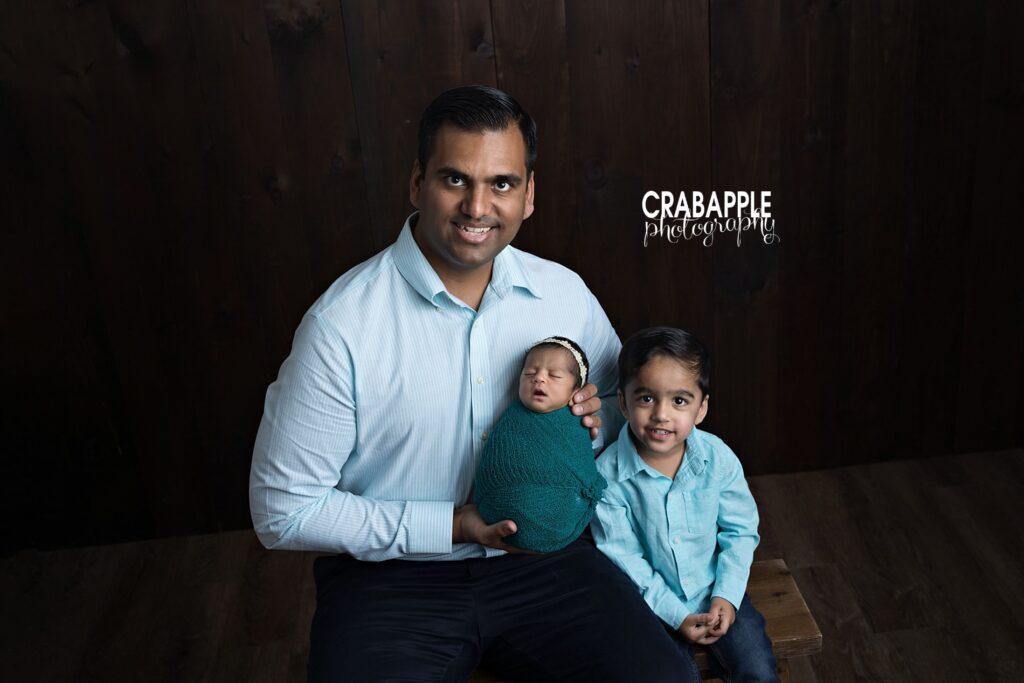 Newborn baby photos in Salem NH of a father holding his newborn daughter with toddler son
