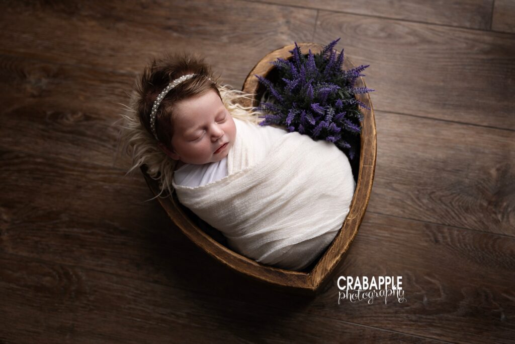 Using props such as faux flowers and heart shaped wooden bowl for newborn photography