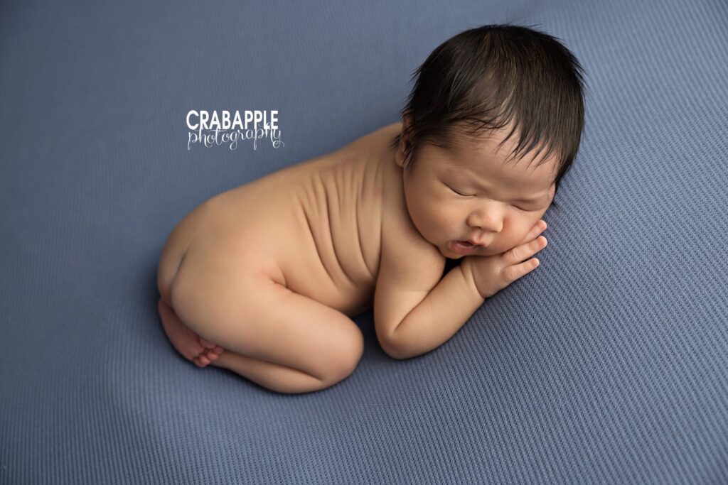 Newborn baby boy resting on a blue backdrop during a Quincy MA newborn photoshoot
