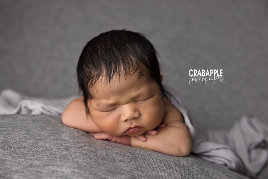 Newborn baby boy posed with chin on hands during a studio newborn photoshoot in Quincy MA
