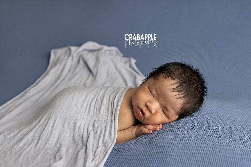 Newborn baby boy wrapped in soft neutral tones during a Quincy MA studio newborn photoshoot
