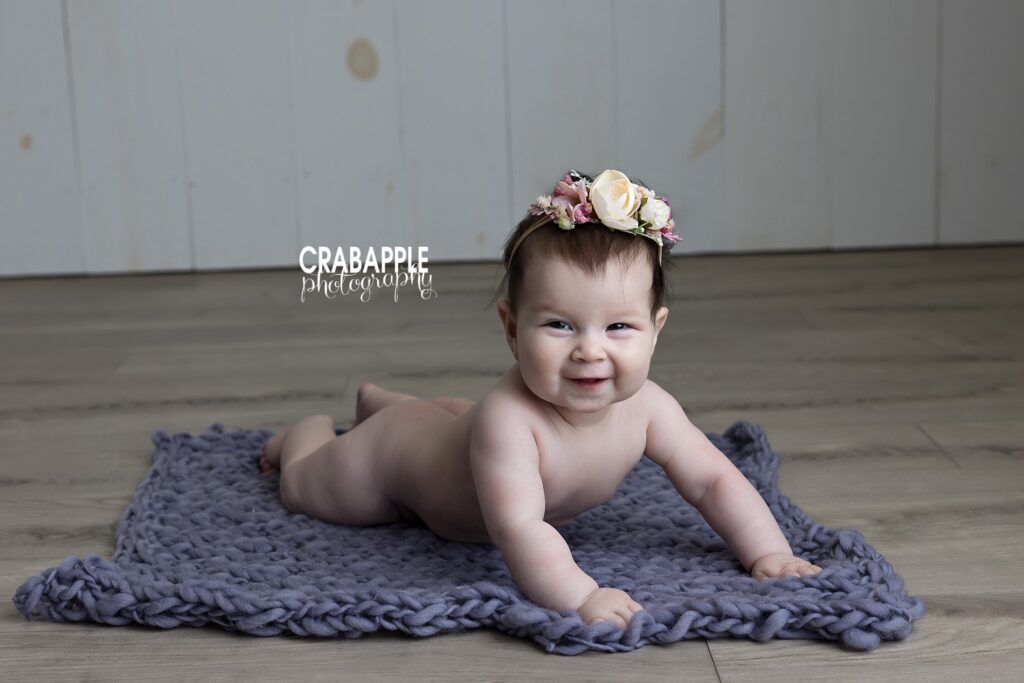 Portrait of smiling baby girl doing tummy time during 6 month sitter session photos