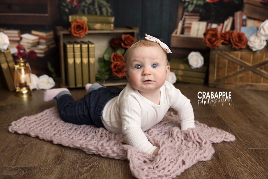 Baby sitting on the floor during Valentine’s Day mini sessions with soft props and florals