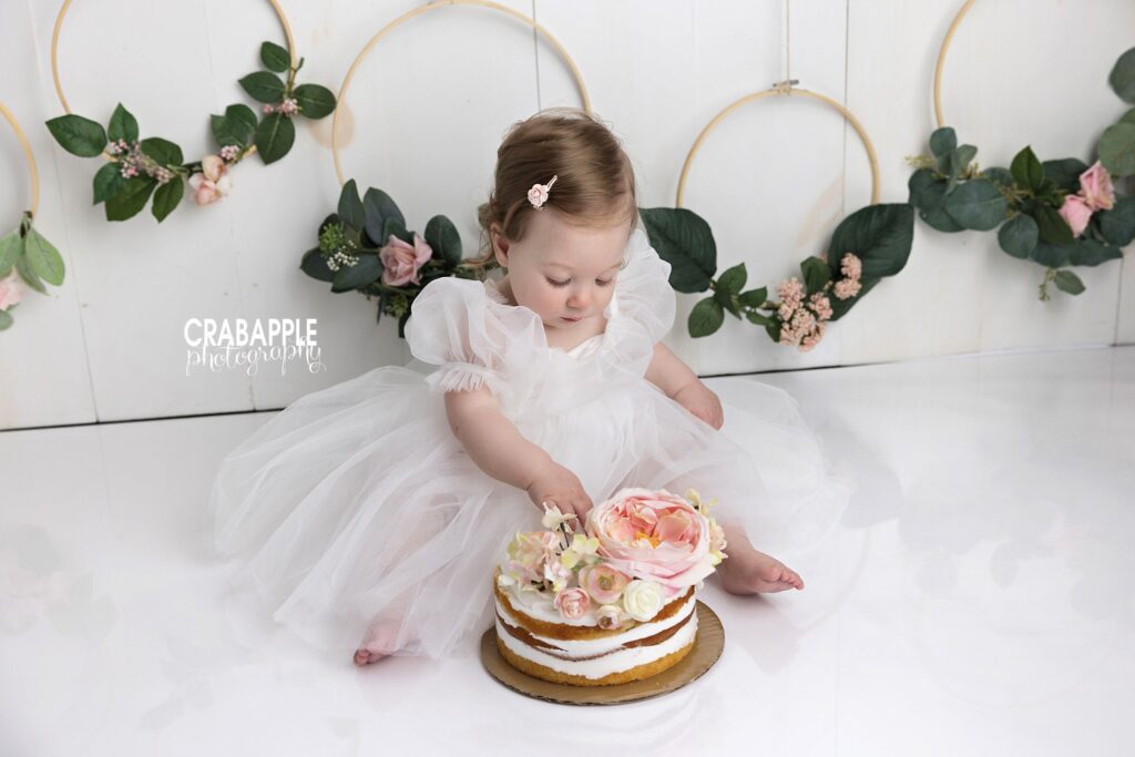 baby reaching for cake during first birthday photos
