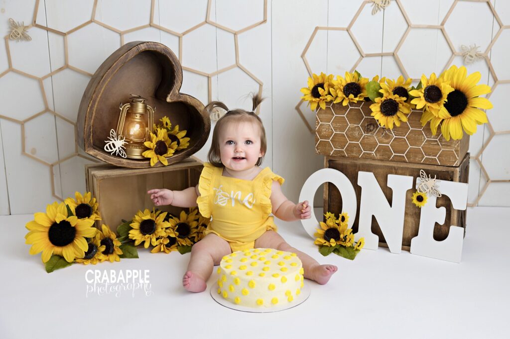 Joyful baby celebrating a first birthday with a sunflower cake smash in a bright studio photoshoot
