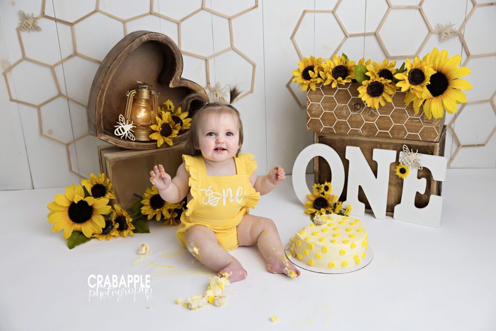 Timeless cake smash photography featuring a baby surrounded by sunflowers in a Woburn MA studio

