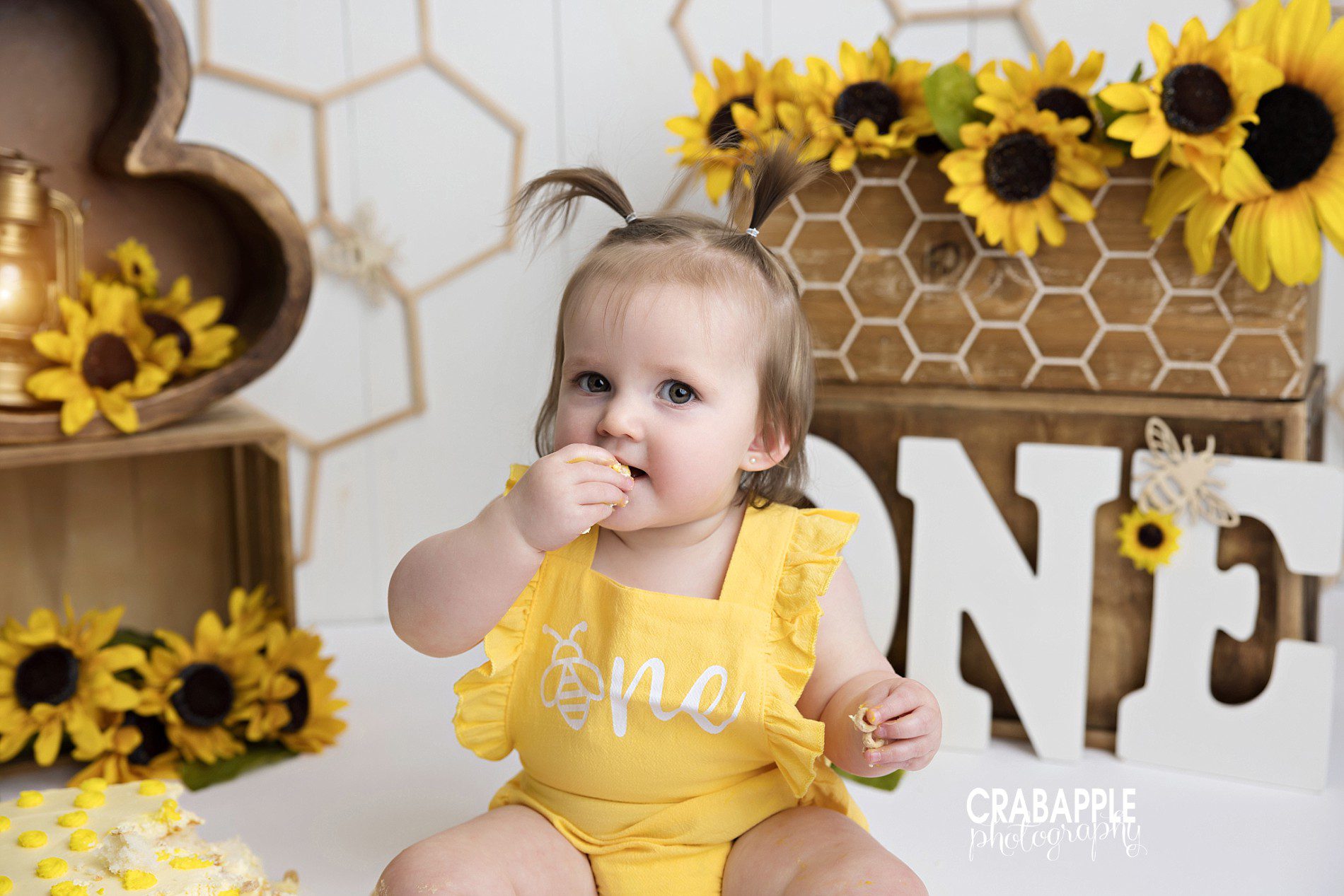 Close-up portrait of baby enjoying cake during a sunflower-themed cake smash photoshoot
