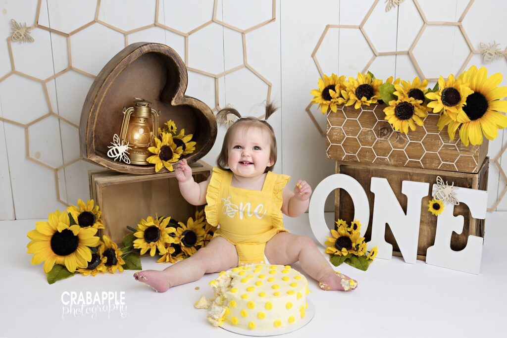 Bright floral baby cake smash photoshoot with sunflowers and a cheerful studio setup
