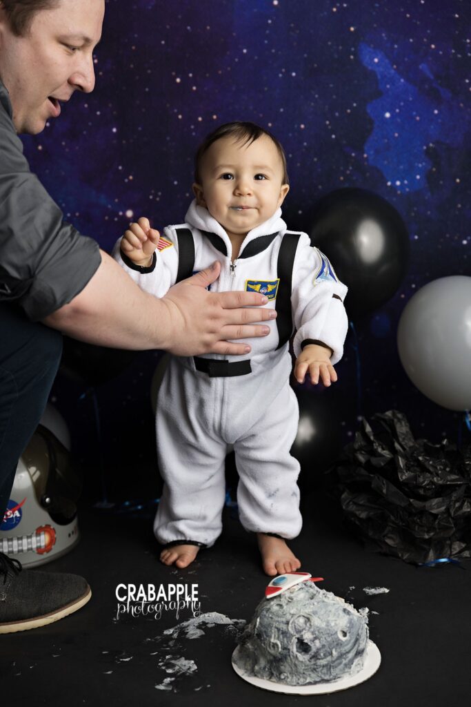 parent helping baby stand during cake smash session
