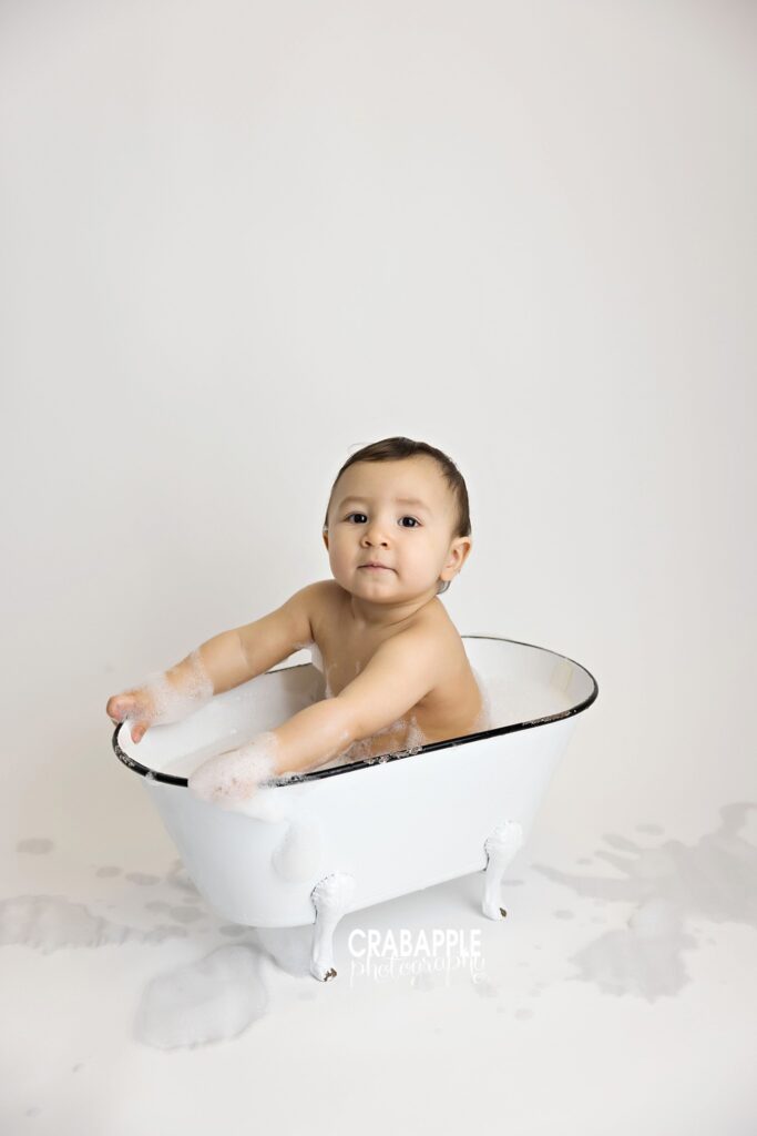 baby sitting in white tub after cake smash with clean background
