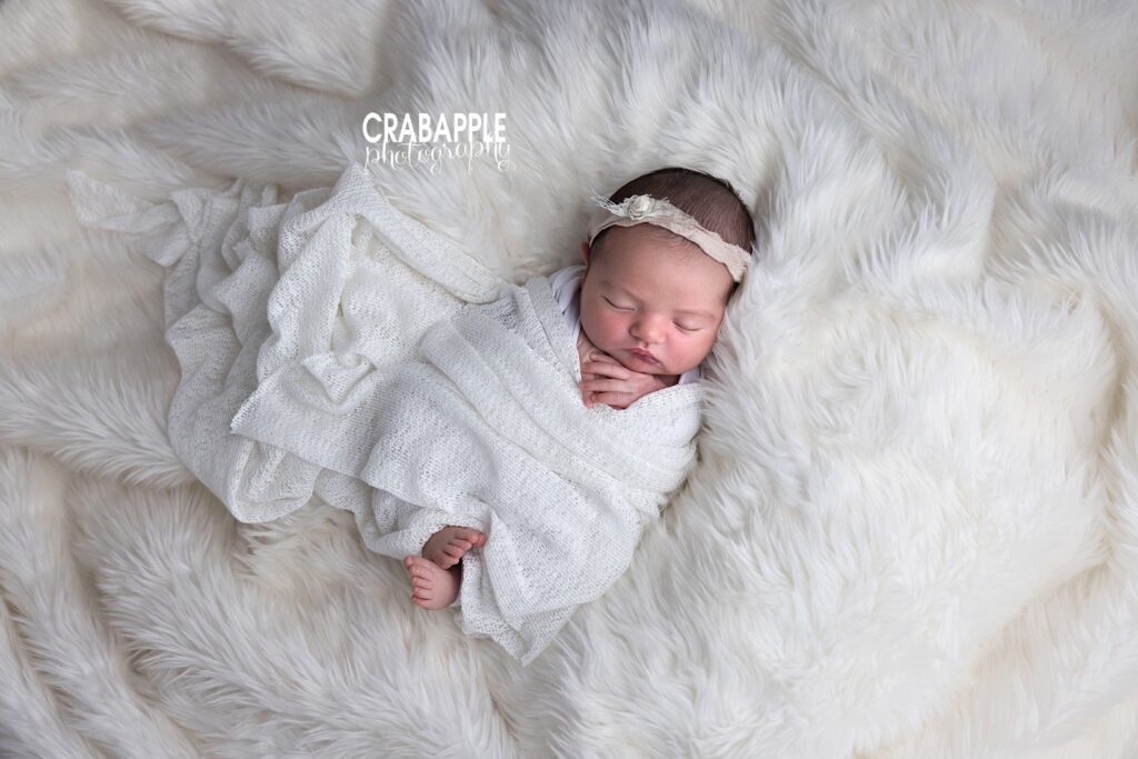 Light and Airy Newborn Session Newborn baby girl wrapped in soft white blanket with delicate accents in Andover MA studio