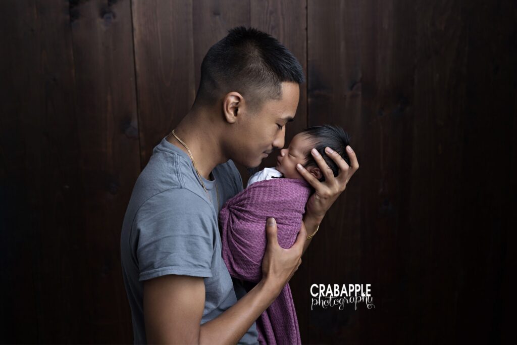 Photo of father holding newborn daughter nose to nose