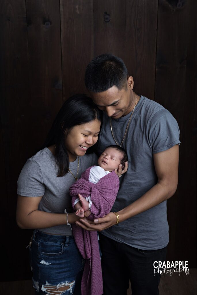 parents holding newborn baby in soft neutral studio setting from Andover newborn photographer
