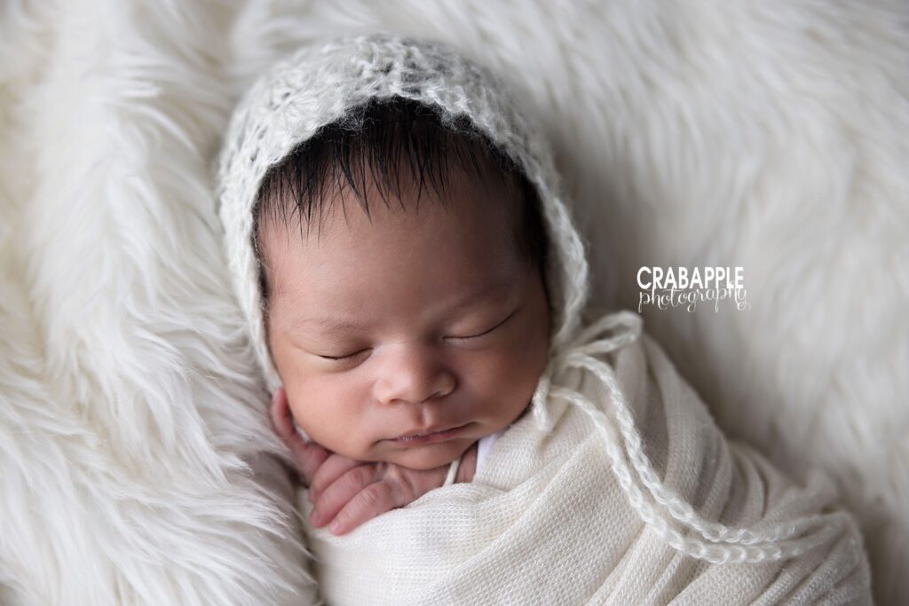 newborn wrapped in neutral fabric on simple background
