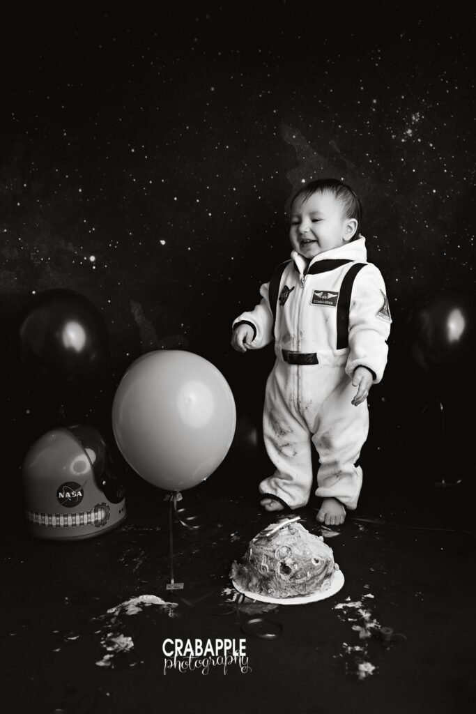 baby standing near cake with space themed backdrop
