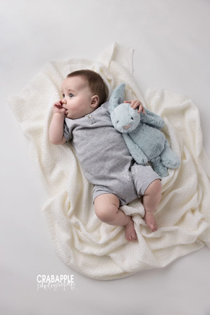 Baby boy sucking thumb and holding stuffed animal sitter session baby photography 8 month photo outfit ideas