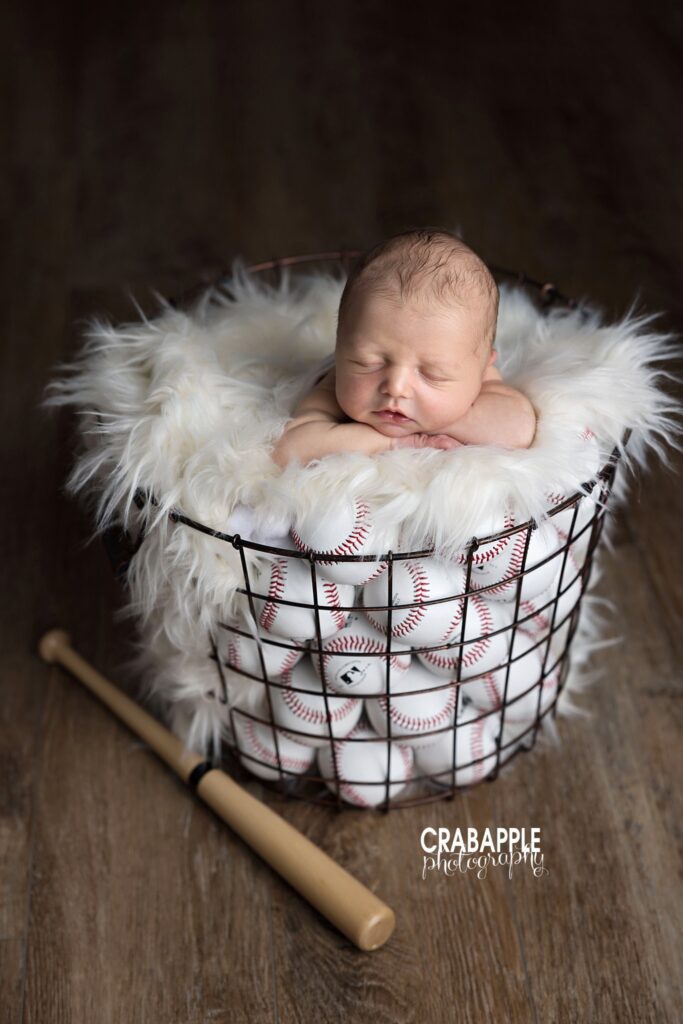 baby boy posed in basket with baseballs
