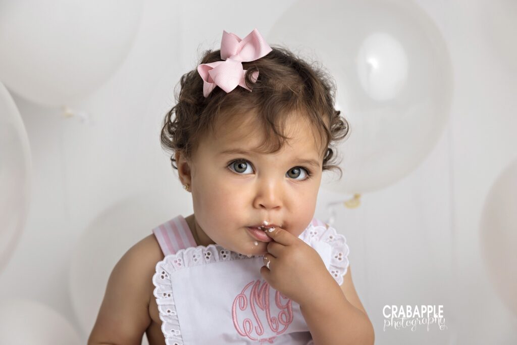 baby girl eating cake during first birthday photoshoot by Southborough baby photographer
