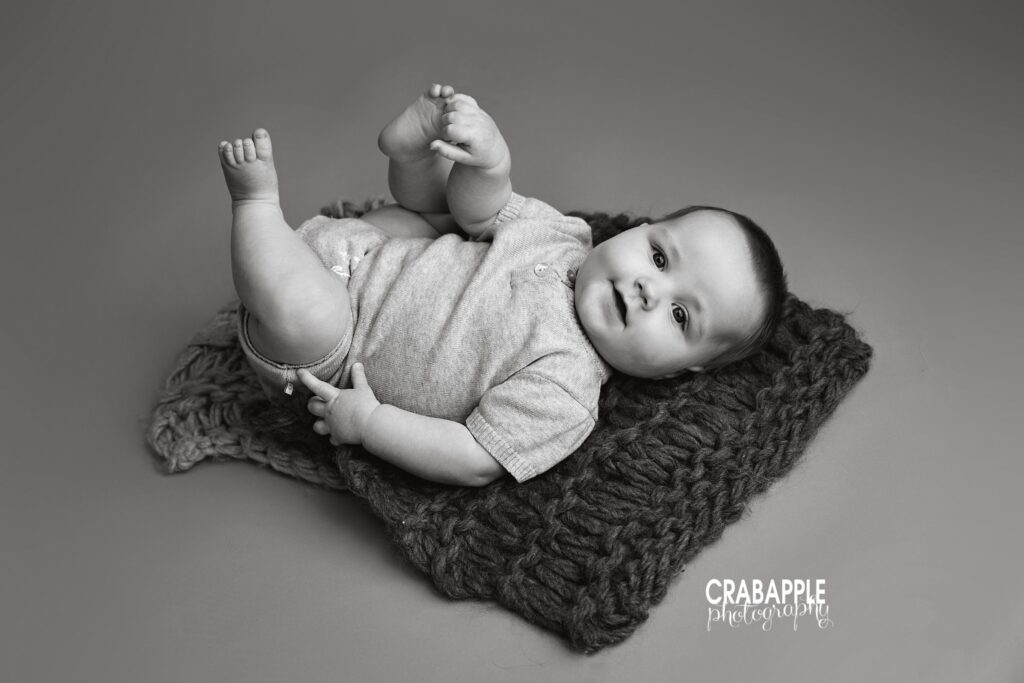 baby milestone photos Amesbury black and white portrait baby lying on back on chunky knit blanket 