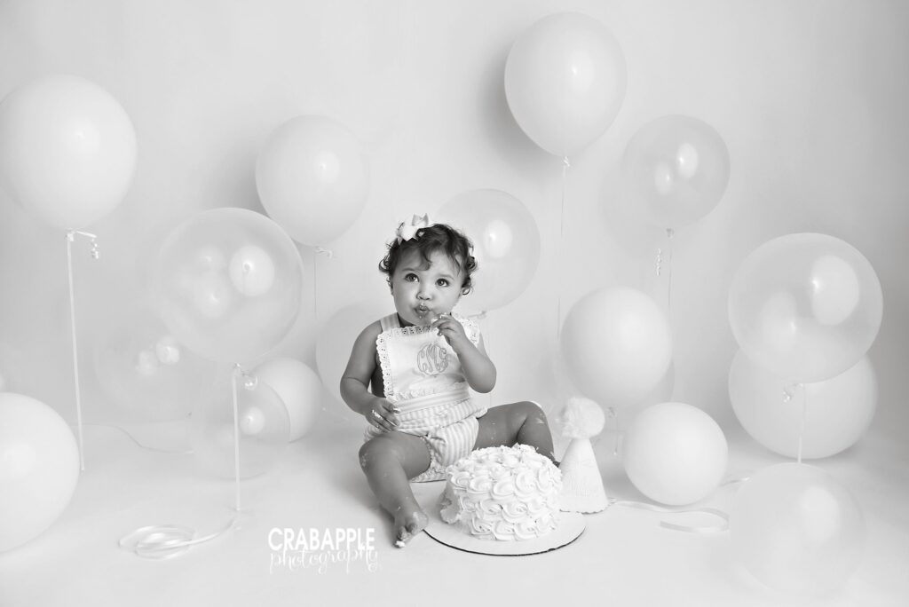 black and white cake smash photo with light colored backdrop and balloons