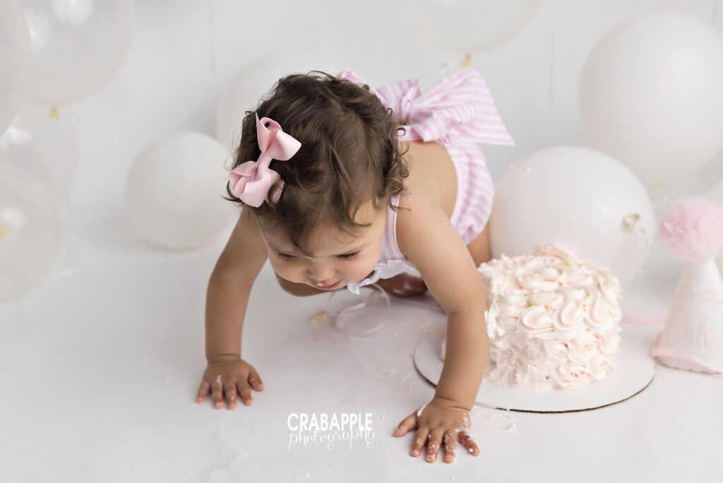 baby girl crawling during cake smash session white backdrop during baby milestone photos
