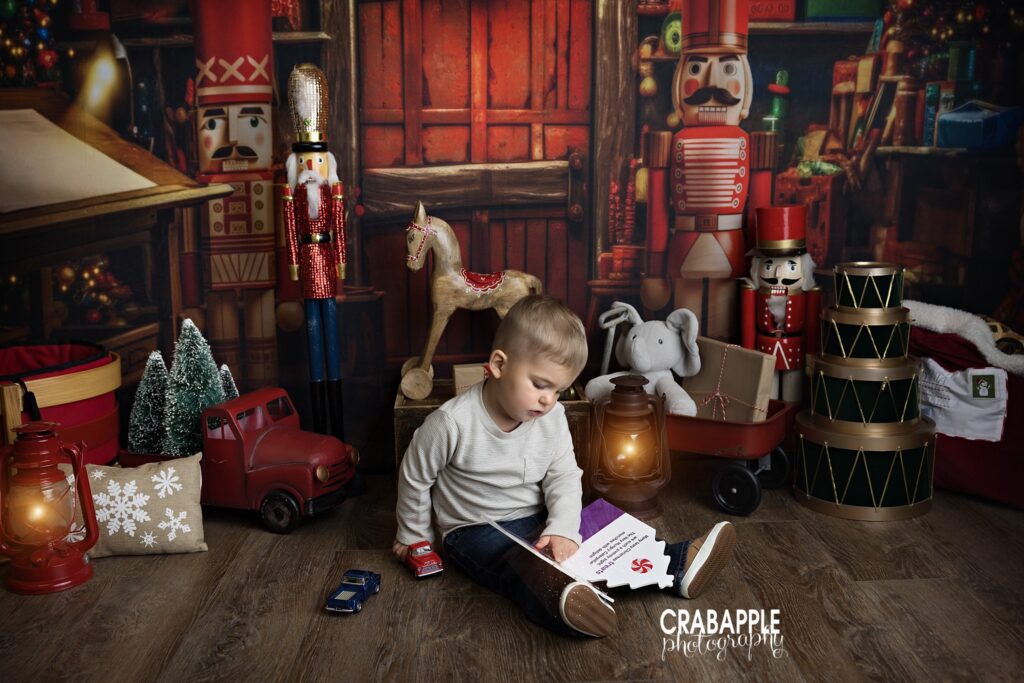 Toddler reading a book and playing with cars on Christmas set