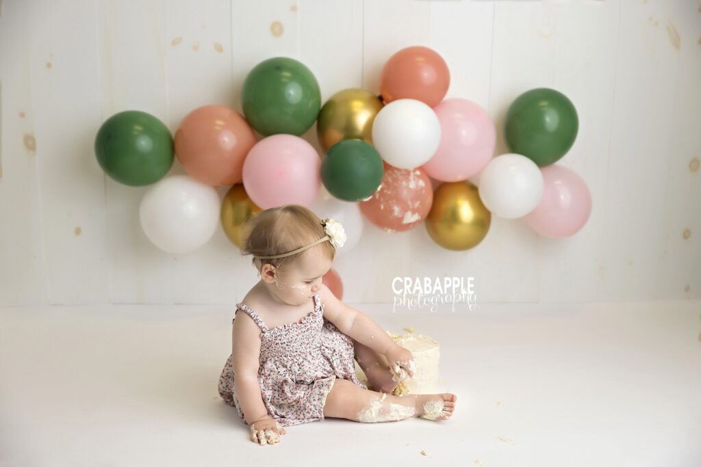 baby girl touching white cake during cake smash session
