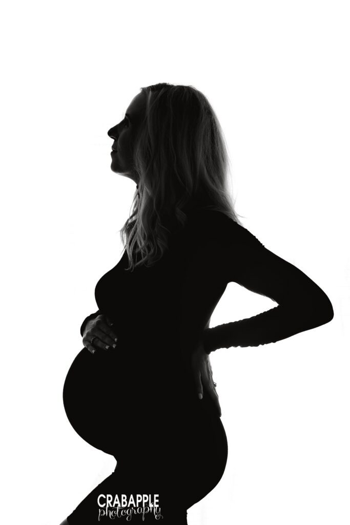 side profile silhouette of pregnant mother standing in studio
