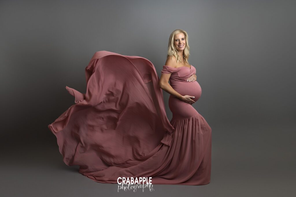pregnant woman in flowing gown with wind movement in studio maternity session
