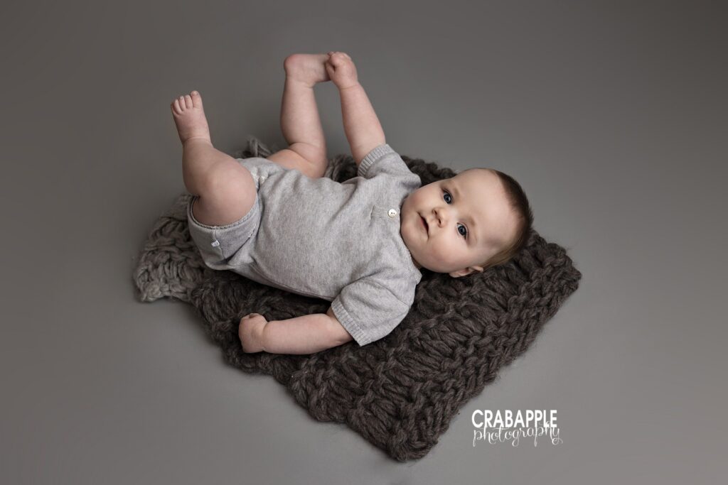 Baby boy lying on back and grabbing toes baby milestone photos Amesbury