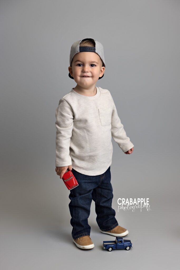 toddler boy standing smiling gray backdrop studio
