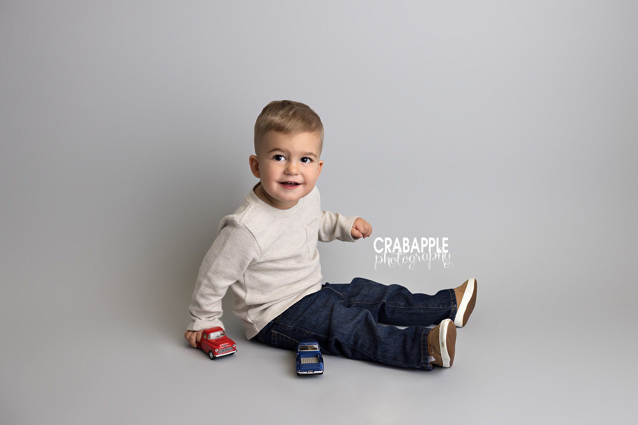 Toddler plays with toy trucks in relaxed classic toddler photos