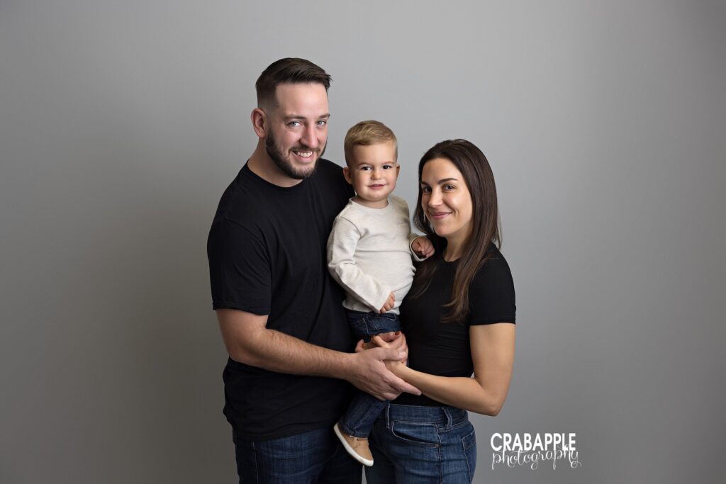 parents holding toddler studio portrait gray background