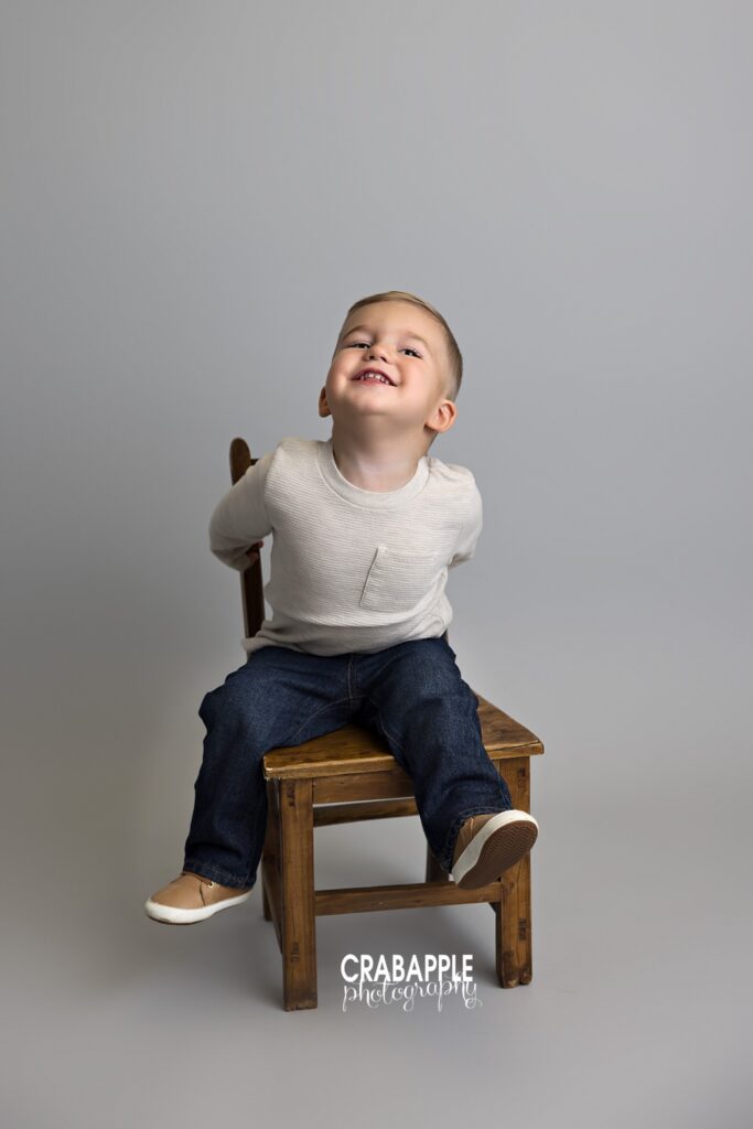 toddler sitting on wooden chair studio portrait
