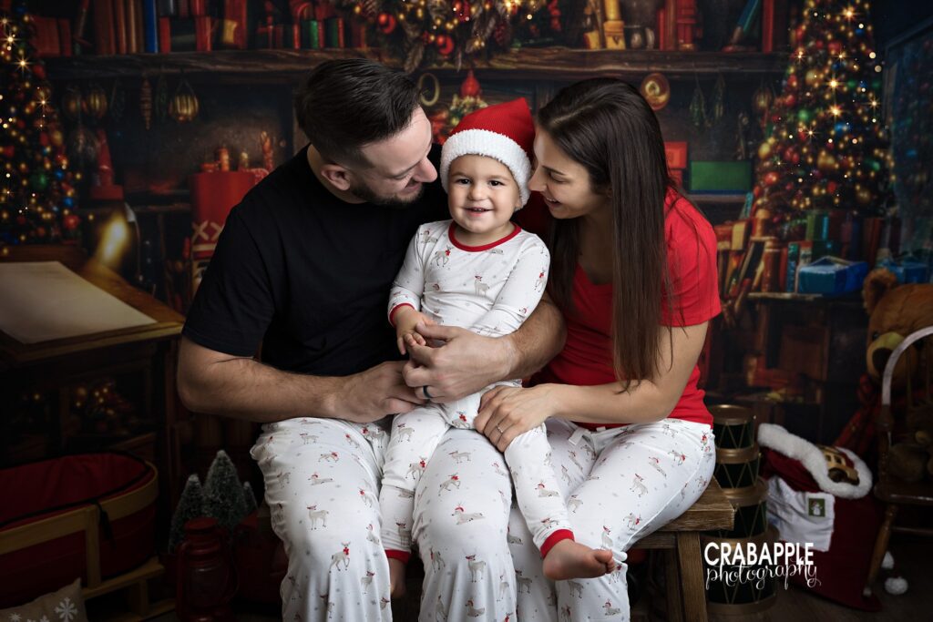 Parents snuggle with their toddler all in Christmas pajamas during holiday photos