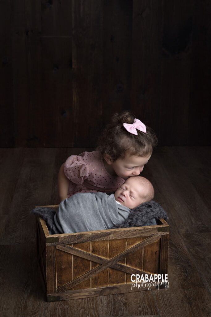 Toddler sister gives newborn brother a kiss during newborn photography Tewksbury session