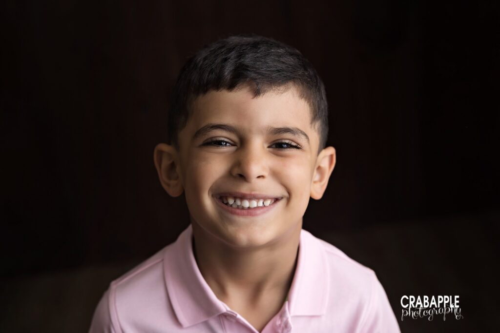 older brother smiling studio portrait during during baby milestone photos
