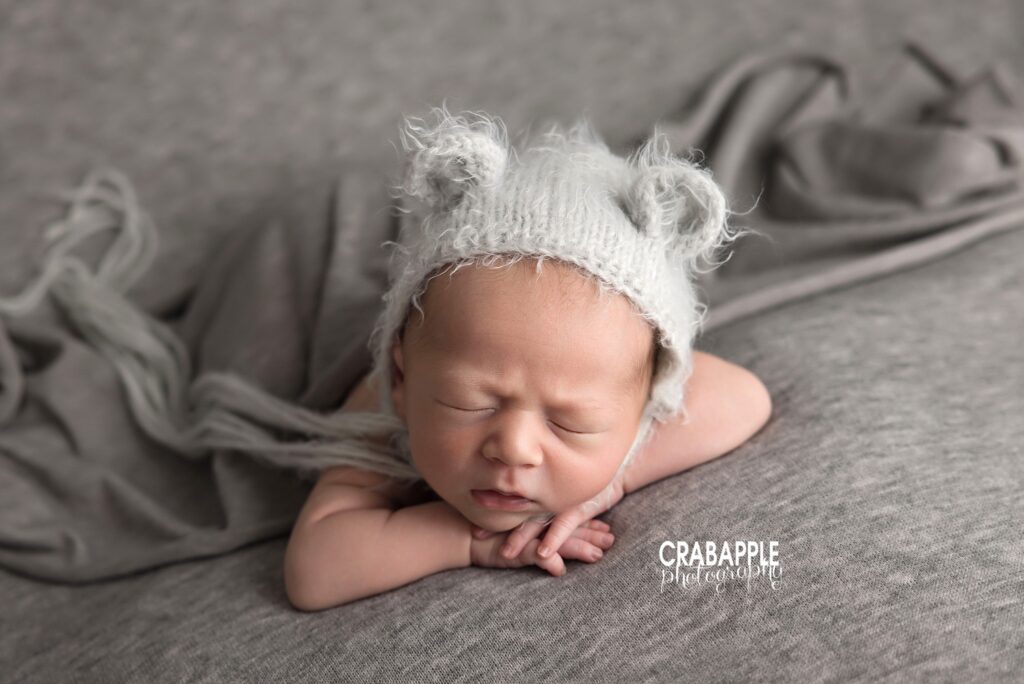 Newborn baby boy posed with chin resting on hands and knit hat