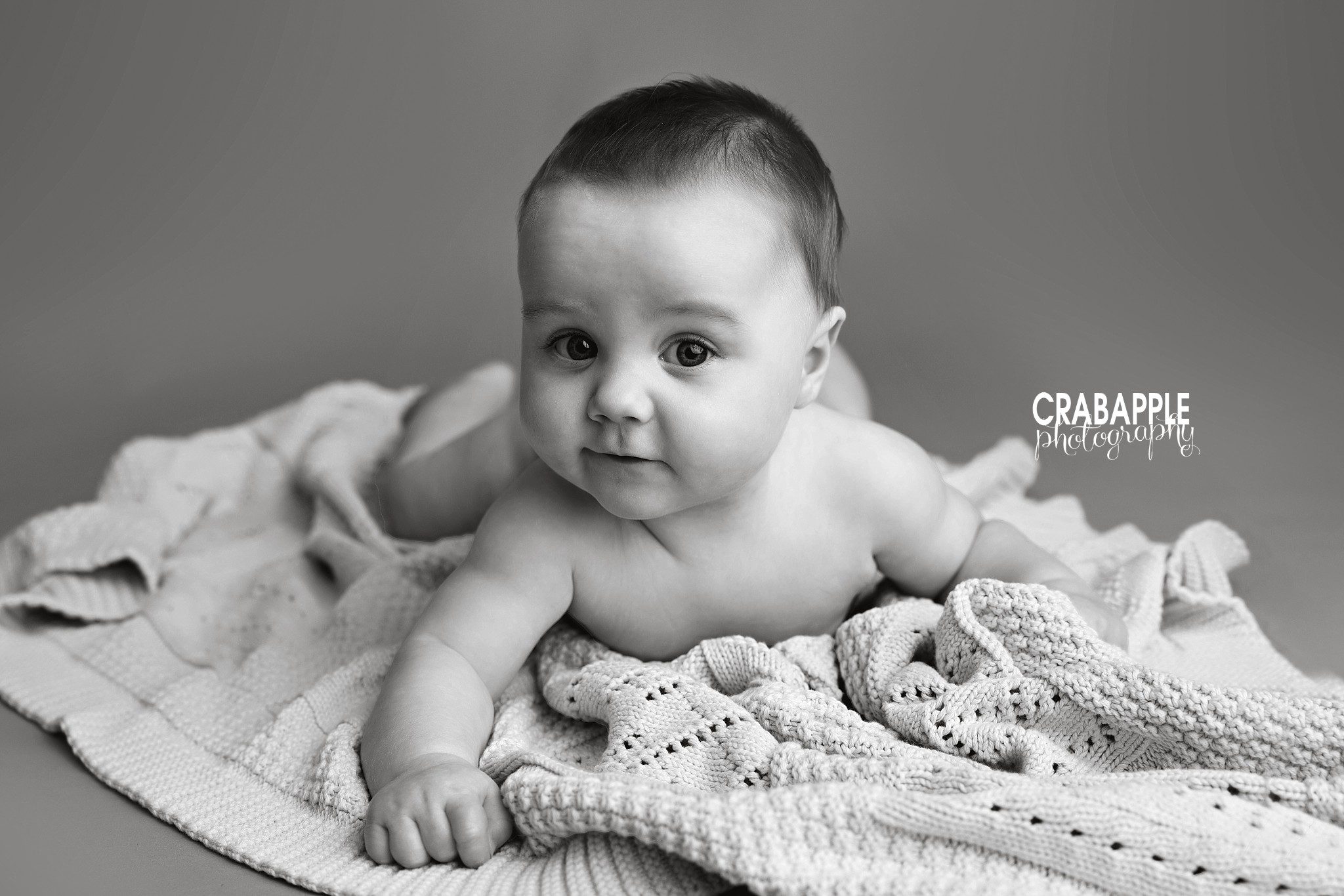 Black and white tummy time photo of 8 month old baby boy during portrait session in Andover MA