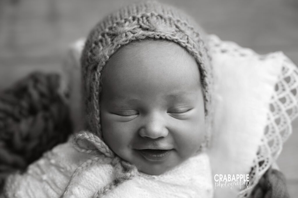 Black and white close up portrait of newborn baby girl with slight smile for newborn wall portrait display
