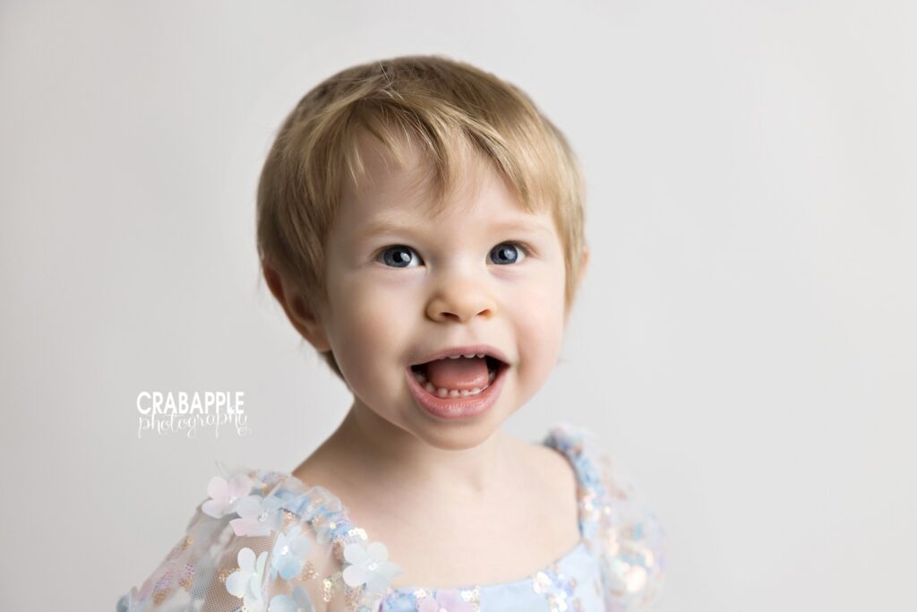 Close-up portrait of smiling two year old girl in light blue dress

