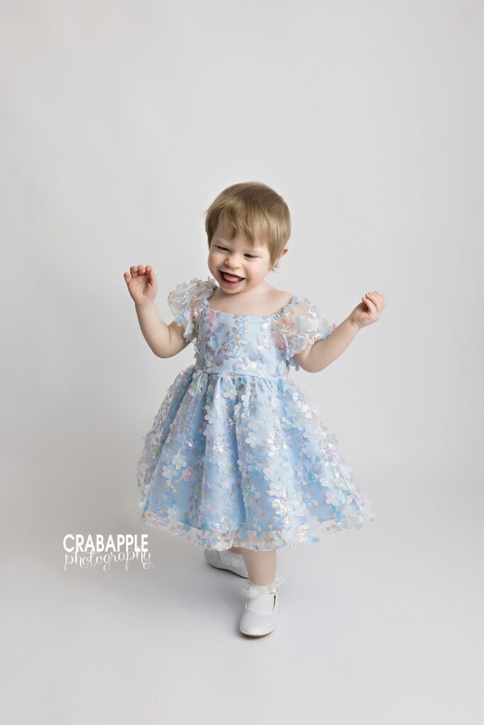 Playful toddler portrait with movement and laughter on white backdrop
