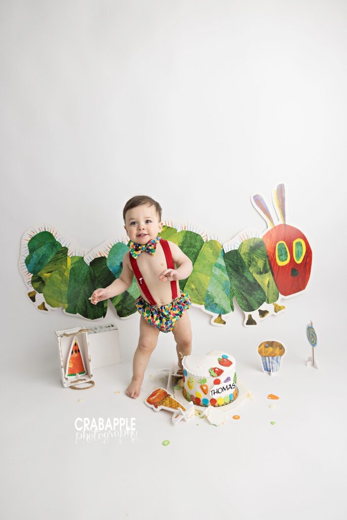 One year old boy standing during Very Hungry Caterpillar themed cake smash
