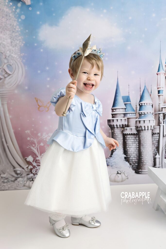 Toddler girl in blue princess dress with star wand during Cinderella themed portrait session
