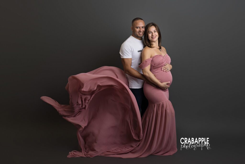 Expecting parents posing together during maternity session with flowing pink gown
