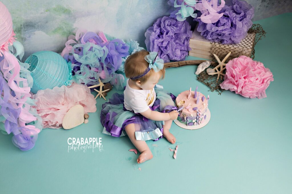Overhead portrait of baby girl during pastel ocean themed cake smash
