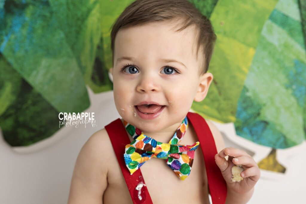 Close up portrait of smiling baby boy during colorful cake smash session
