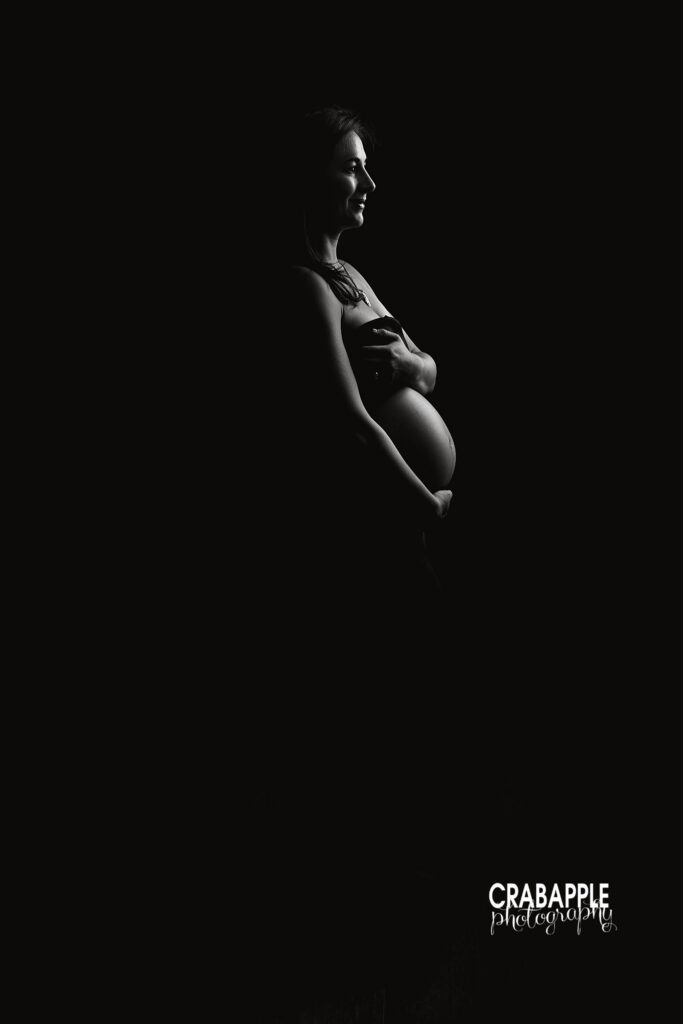 Dramatic black and white maternity silhouette portrait with artistic lighting
