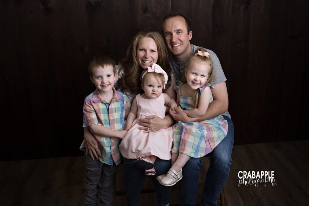 Parents with three children during relaxed family portrait session in Andover MA studio
